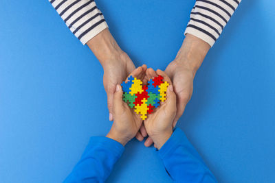 Low section of man holding multi colored blue background