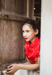 Portrait of smiling young woman against red wall