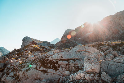 Sun shining through rocks against clear sky