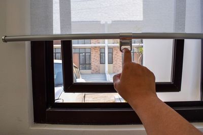 Person closing window shutter at home