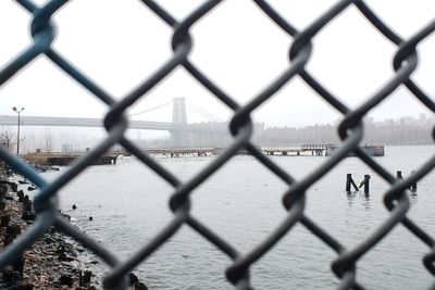 Williamsburg bridge from behind a fence from domino park