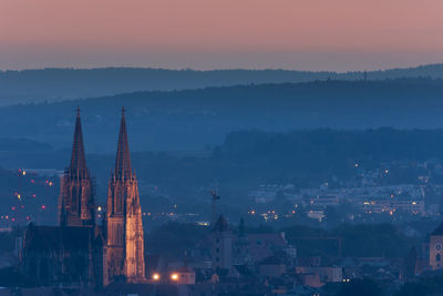 Illuminated buildings in city against sky during sunset