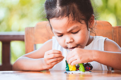 Cute girl making molecule model on wooden table in porch