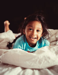 Portrait of smiling girl lying on bed at home