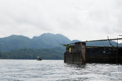 Boat floating on sea against mountains