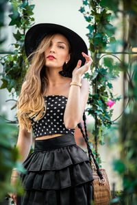 Portrait of woman wearing hat standing against plants