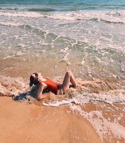 Side view of woman lying on shore at beach