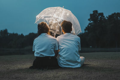 Rear view of man and woman with umbrella