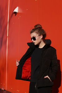 Teenage girl posing against red wall
