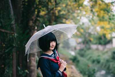 Woman holding umbrella standing in rain during rainy season