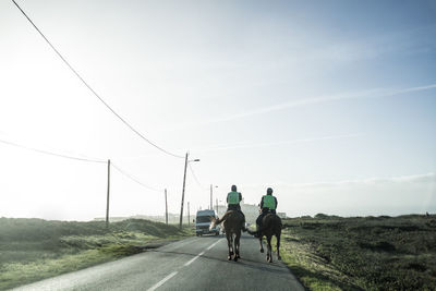 Rear view of people riding bicycle on road