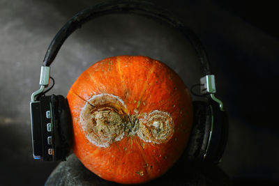 Close up orange pumpkin wearing headset represent a people who love music so much