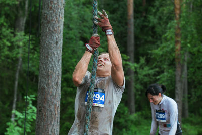 Full length of man standing by tree trunk in forest