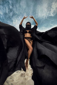 Low angle view of woman with arms raised against sky