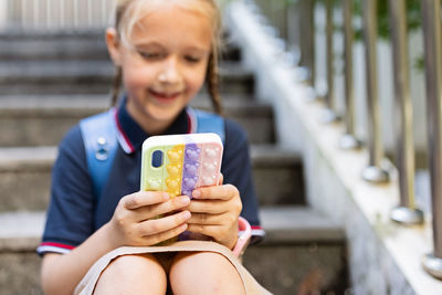 Portrait of girl using mobile phone while sitting outdoors