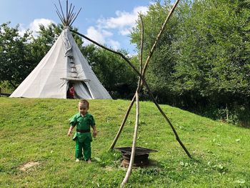 Boy standing against tent on field