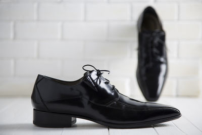 Close-up of black shoe against white wall