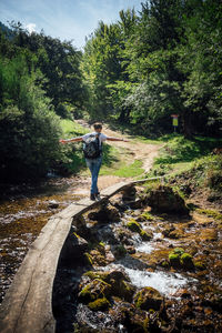 Full length of woman standing by stream in forest