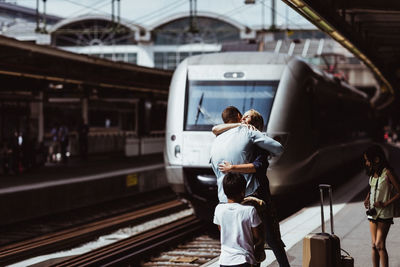 Children looking at parents embracing on railroad station platform