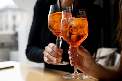 Midsection of women toasting drinks in restaurant