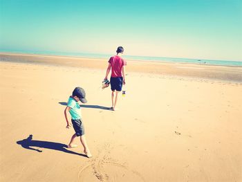 Siblings on beach during sunny day