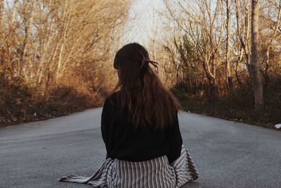 Rear view of woman walking on road amidst trees