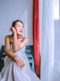 Young woman sitting by window at home