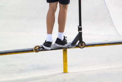 Low section of man with push scooter standing on railing