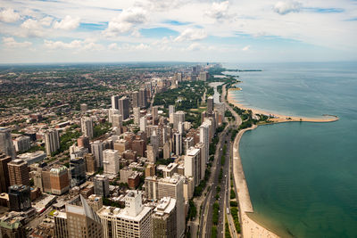 Aerial view of city by sea against sky