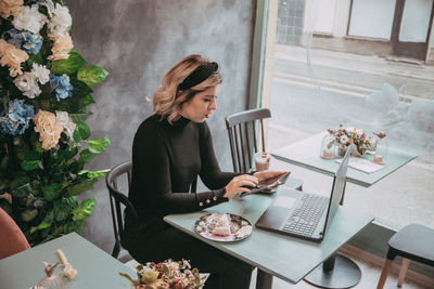 Young woman using mobile phone while sitting on table