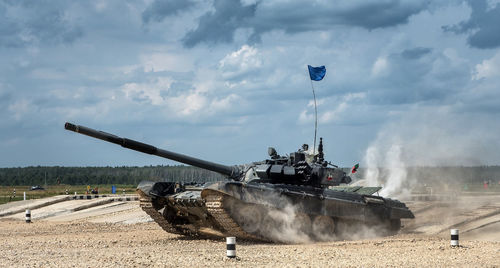 Tank moving at patriot park against cloudy sky