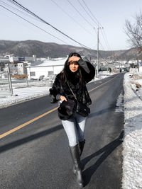 Young woman standing on road in city during winter