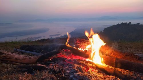 Bonfire on wooden structure against sky during sunset
