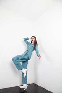 Young woman standing against white wall