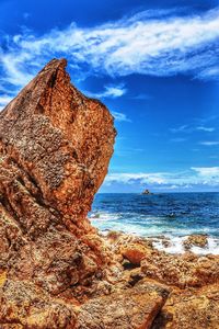 Rock formation on beach against cloudy sky