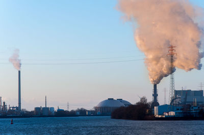 Smoke emitting from factory against sky