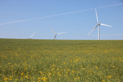 Wind turbines on field against clear sky