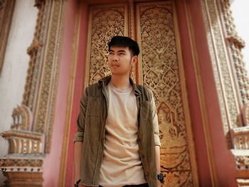 Portrait of young man standing against temple structure 