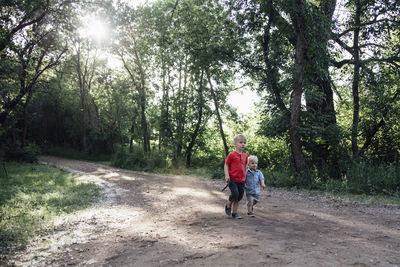 Brothers walking on dirt road in forest