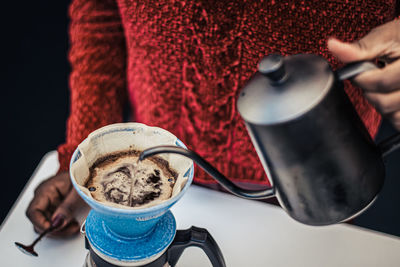 Black skin girl preparing or brewing black coffee with a teapot and cloth or paper filter