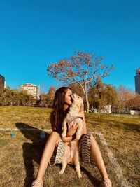 Young woman with dog on plant against sky