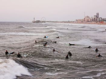 High angle view of people surfing on sea against sky