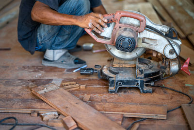 Low section of man holding electric saw in workshop