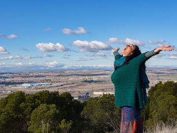 Young woman standing against sky