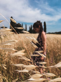 Close-up of woman standing in wheat field against sky
