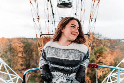 Smiling young woman looking away while sitting in ferris wheel