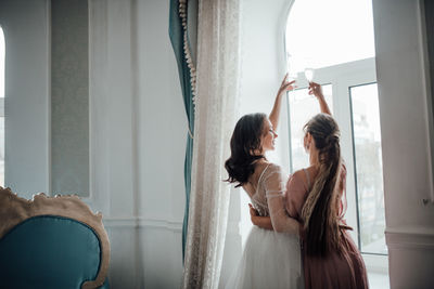 Bridesmaid and bride holding champagne flute