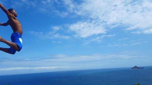 Man jumping in sea against sky