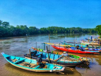 Boats moored in sea against clear blue sky