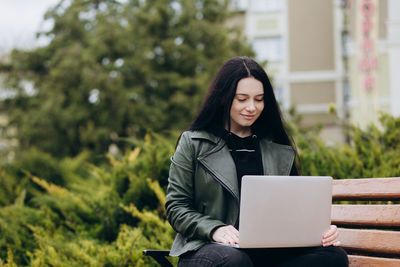 Young woman using laptop while sitting on field